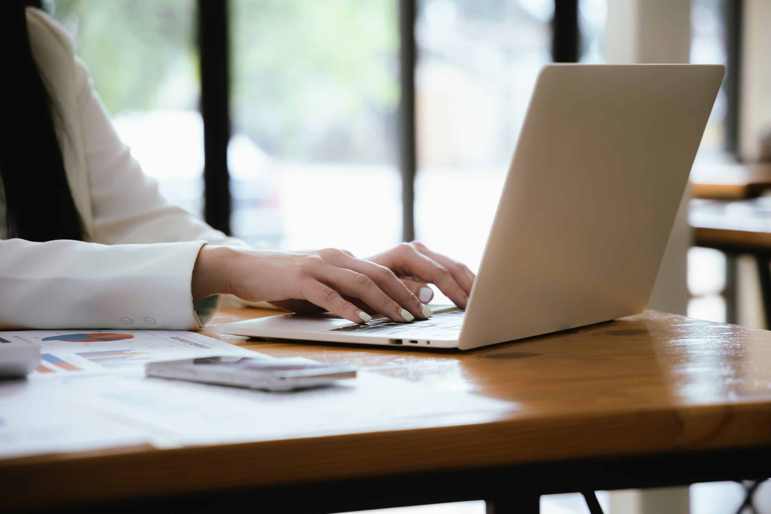 A,Focused,Businesswoman,Uses,A,Laptop,And,A,Calculating,Machine